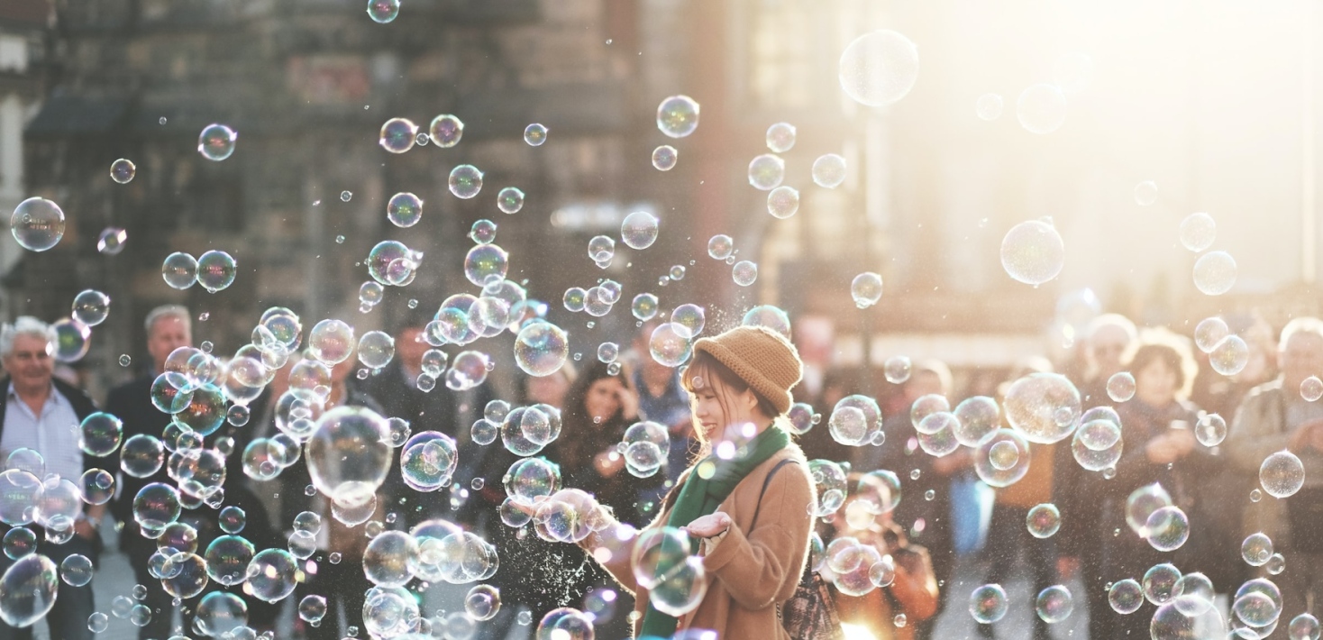Girl with soap bubbles standing in a crowd